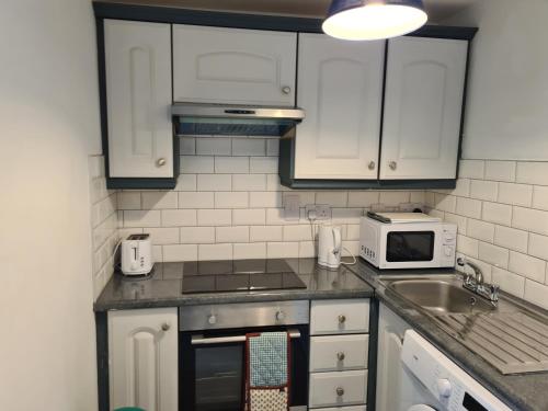 a kitchen with white cabinets and a sink and a microwave at St Patricks Avenue Apartment, H91A4W7 in Galway