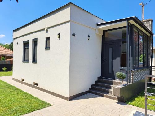 a white house with a black door at Relax Vendégház in Dunapataj