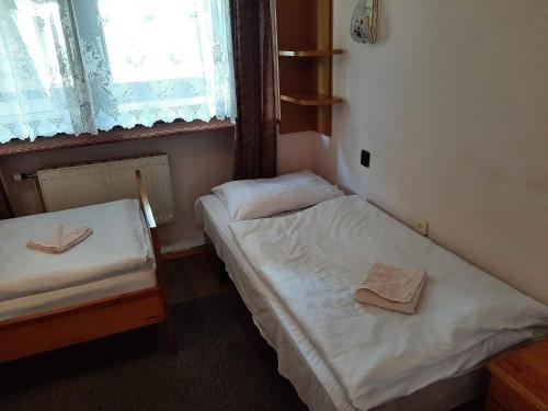 two twin beds in a room with a window at Usługi hotelarskie Karpacz in Karpacz