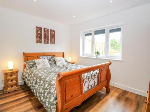 a bedroom with a wooden bed and two windows at Walnut Shade in Attleborough