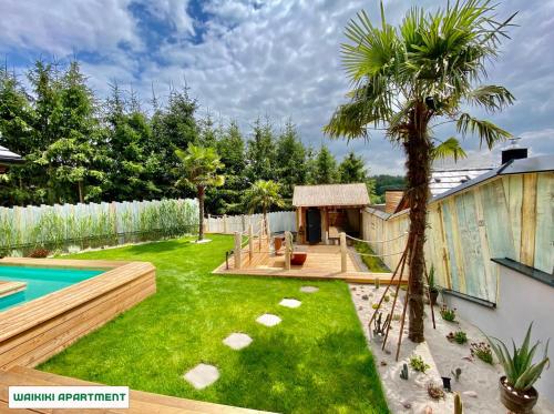 a backyard with a swimming pool and a palm tree at You and Me Apartments in Prosenická Lhota