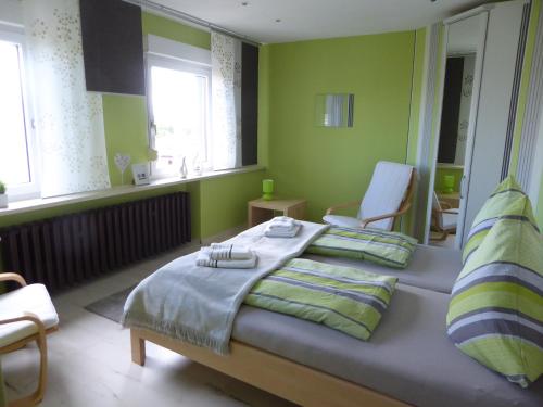 a bedroom with a bed and a chair and windows at Ferienwohnung Hagebuttenweg in Thale