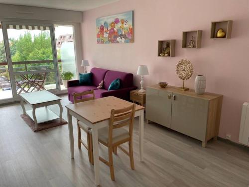 a living room with a table and a couch at Petit Studio Zen avec parking gratuit réservé in Houlgate