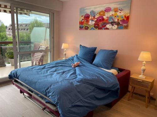 a bedroom with a bed with a blue comforter at Petit Studio Zen avec parking gratuit réservé in Houlgate
