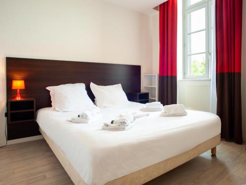 a bedroom with a large white bed with towels on it at Vacancéole - Le Duguesclin in Dinan