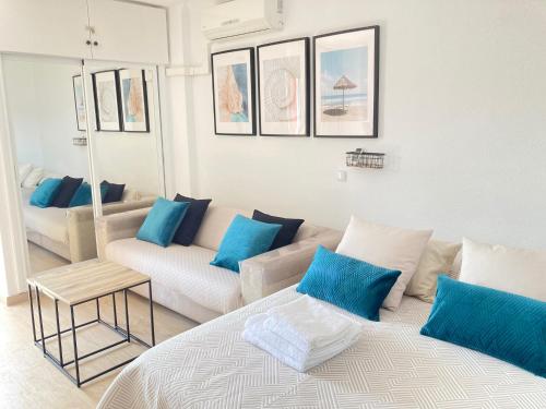 a white living room with blue pillows and a couch at Minerva Paradise in Benalmádena