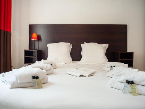 a bed with white pillows and towels on it at Vacancéole - Le Duguesclin in Dinan