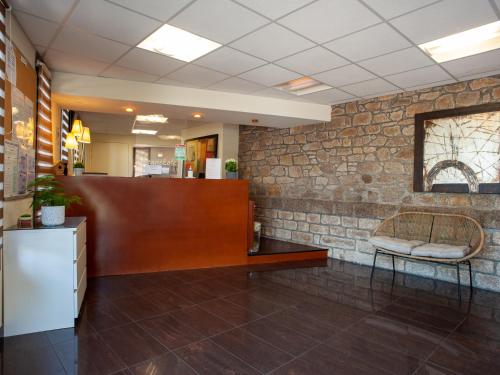 a waiting room with a chair and a brick wall at Vacancéole - Le Duguesclin in Dinan
