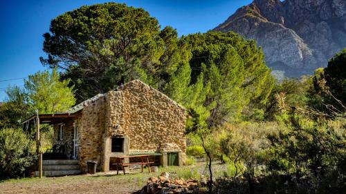 a stone house with a mountain in the background at Welbedacht Game & Nature Reserve in Tulbagh