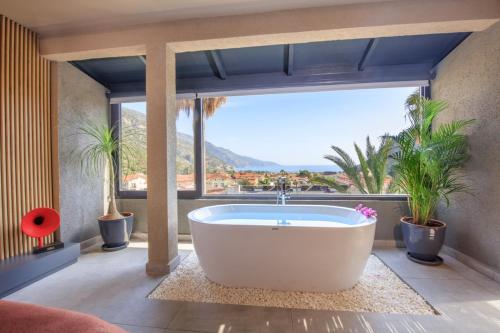 a bath tub in a room with a large window at Morina Deluxe Hotel in Oludeniz