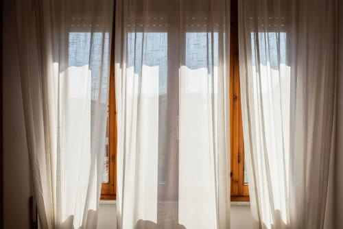 a window with white curtains in a room at Anice, app. Lido di Camaiore private parking in Camaiore