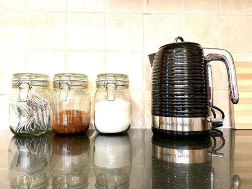 a counter with four jars of milk and a blender at NEW! Luxury YELLOW HOUSE Bright Modern Detatched Home with PRIVATE PARKING, NETFLIX Close Luton, M1, and AIRPORT Ideal for Families, Professionals, Consultants, LONGER STAY OPTIONS in Caddington