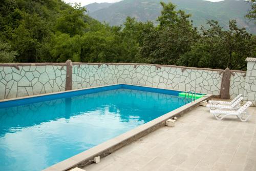 a swimming pool with two chairs and a fence at Spitak tun in Ijevan