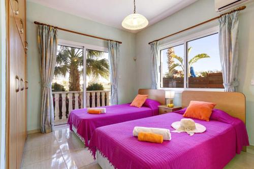 Duas camas roxas num quarto com varanda em Villa Azalea by Villa Plus em Pegeia ou Pegya