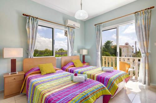 two beds in a bedroom with a balcony at Villa Gardenia by Villa Plus in Peyia