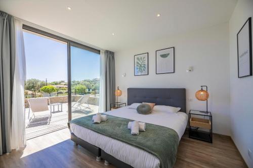 a bedroom with a large bed and a balcony at Villa 18 in Porto-Vecchio