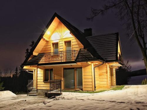 a wooden house in the snow at night at Apartamenty Słodyczki in Nowe Bystre
