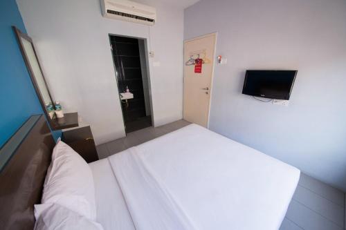 a bedroom with a white bed and a television at Golden Pearl Hotel Near Universiti Tun Hussein Onn Malaysia UTHM in Batu Pahat
