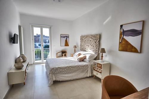 a white bedroom with a bed and a window at EQUORUM Delicious Suite - Ostuni Centro in Ostuni