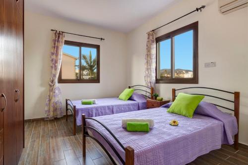 two beds in a room with two windows at Villa Kassiopeia by Villa Plus in Peyia