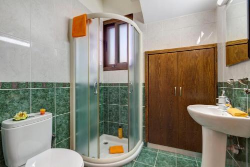 a bathroom with a shower and a toilet and a sink at Villa Kassiopeia by Villa Plus in Peyia