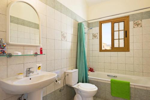 ein Badezimmer mit Toilette, Waschbecken und Spiegel in der Unterkunft Villa Katina by Villa Plus in Peyia