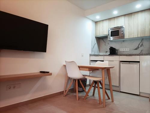 a kitchen with a table and two chairs and a tv at Joan Miró Luxury Torremolinos in Torremolinos