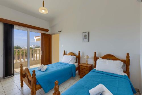 a bedroom with two beds and a balcony at Villa Pandora by Villa Plus in Peyia