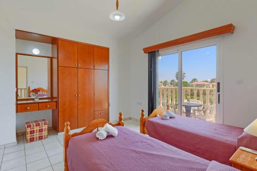 a bedroom with two beds and a balcony at Villa Semeli by Villa Plus in Peyia