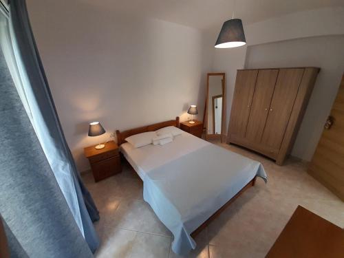 a bedroom with a white bed and two night stands at Χαλκιδική Κρυοπηγή in Kriopigi
