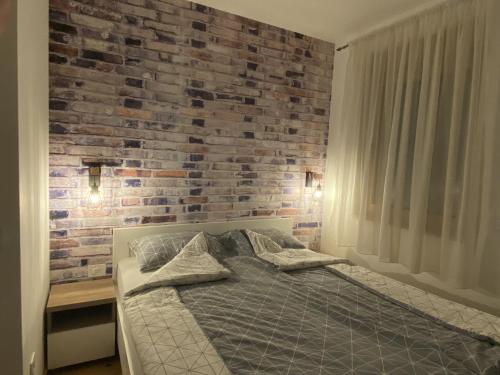 Un dormitorio con una pared de ladrillo y una cama en Aleksić Apartment Zlatibor, en Zlatibor