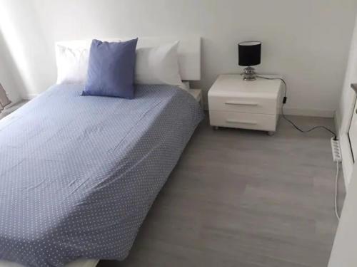 Bel appartement pour vos séjours sur la côte في نيس: غرفة نوم بسرير ومخدة زرقاء وموقف ليلي