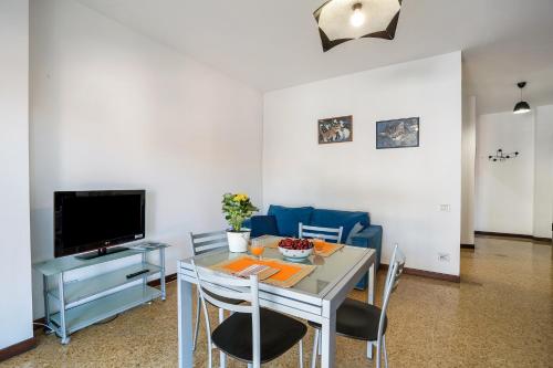 a dining room with a table with chairs and a television at Iris Apartment Lago Maggiore in Angera
