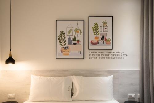 una camera da letto con due immagini di piante sopra un letto di The Way Inn a Taichung