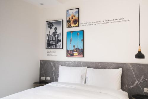 a bedroom with a white bed with four pictures on the wall at The Way Inn in Taichung
