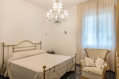 a bedroom with a bed and a chandelier and a chair at Miriam e Carlo in Moneglia