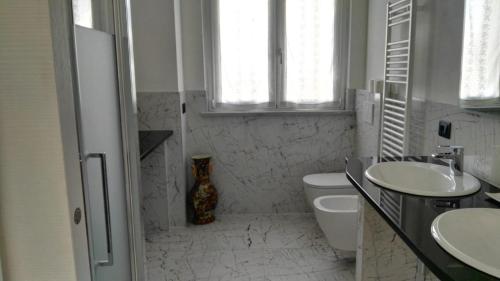 bagno bianco con 2 lavandini e servizi igienici di Casa Bonelli ad Alba