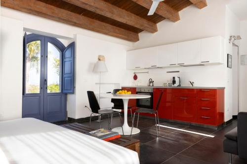 a bedroom with a bed and a kitchen with red cabinets at Masseria del Carrubo in Noto
