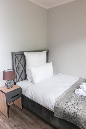 a bed with white sheets and a nightstand with a lamp at Hotel Waldeslust in Kurort Altenberg