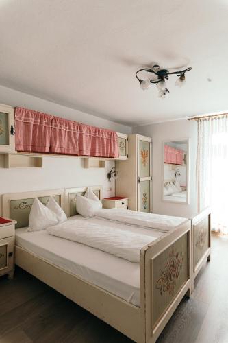 a bedroom with a large bed with white sheets at Gasthof Residence Brugghof & Erlhof in Campo Tures