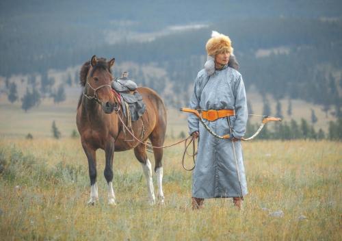 uma mulher ao lado de um cavalo num campo em Doloon Uul em Turt