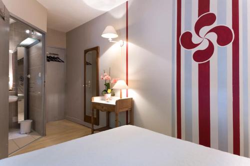 a hotel room with a bed and a bathroom at Le Cèdre Bleu in Ciboure