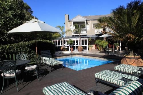 a pool with chairs and a table and an umbrella at Cinnamon Boutique Guest House in Wilderness