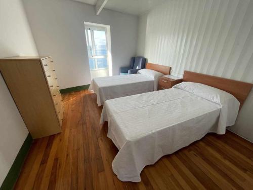 a hotel room with two beds and a wooden floor at Grupo Gontad Casa Baixo da Capilla Corme in A Coruña