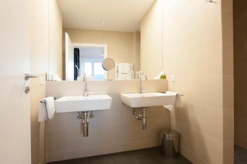 a bathroom with two sinks and a mirror at Boutique Hotel Aichinger in Nussdorf am Attersee
