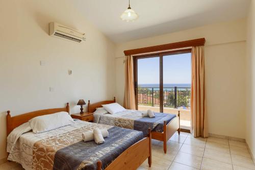 1 Schlafzimmer mit 2 Betten und einem großen Fenster in der Unterkunft Villa Harmony by Villa Plus in Peyia