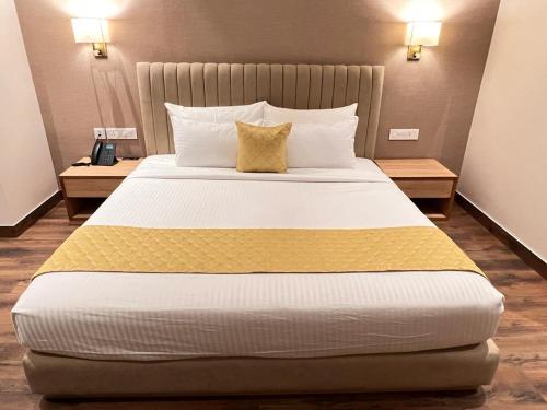 a large bed in a hotel room with two tables at Palasa Hotel in Muzaffarnagar