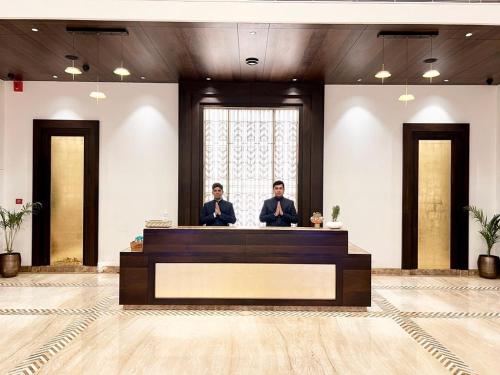 two men standing behind a desk in a room at Palasa Hotel in Muzaffarnagar