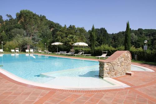 a large swimming pool with chairs and umbrellas at Villa Rigacci Hotel in Reggello