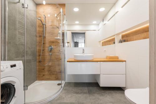 a white bathroom with a sink and a shower at Apartament Sea & City in Kołobrzeg